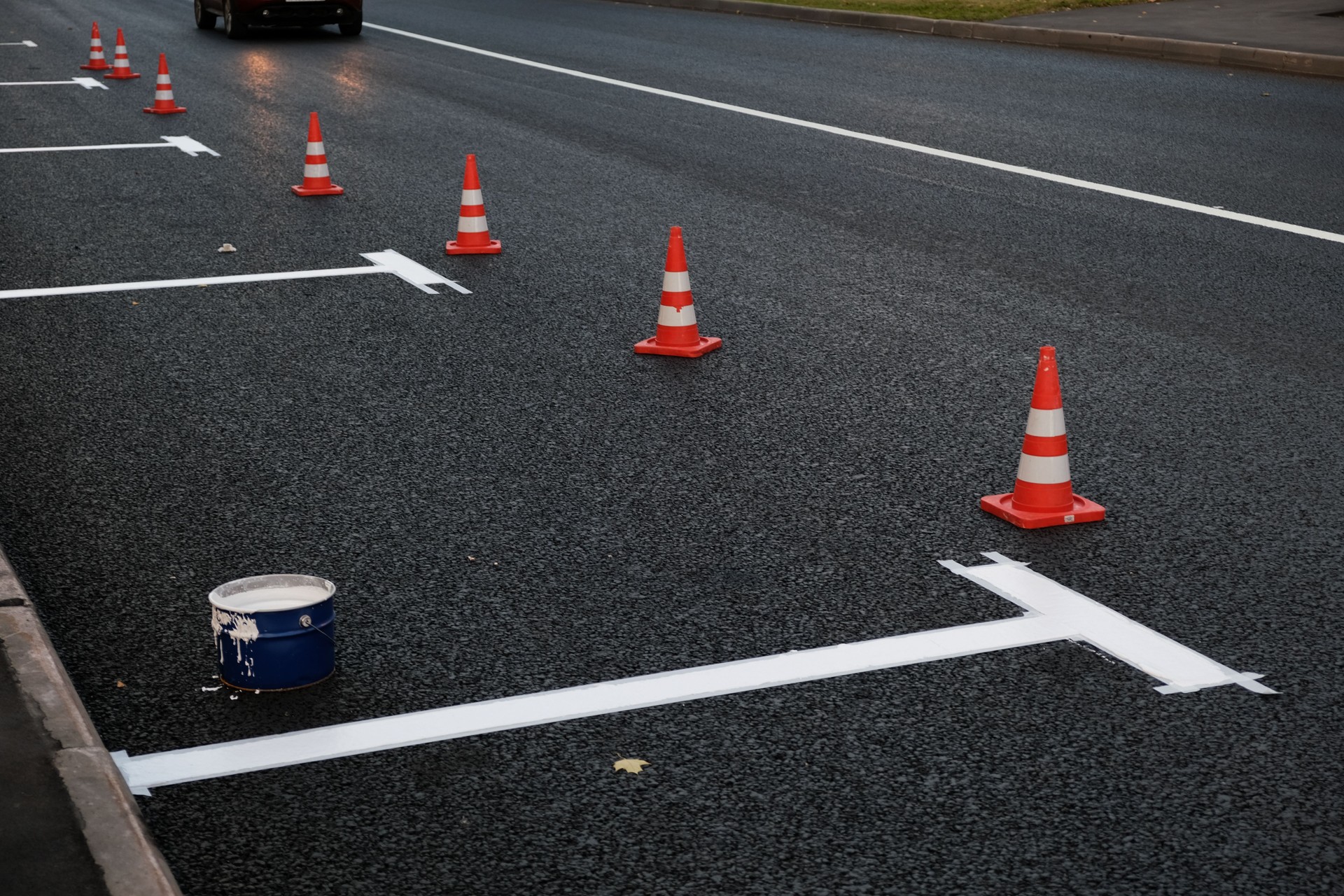 New road markings on asphalt, parking on carriageway along the road. Manual labor, Painting process. Selective focus